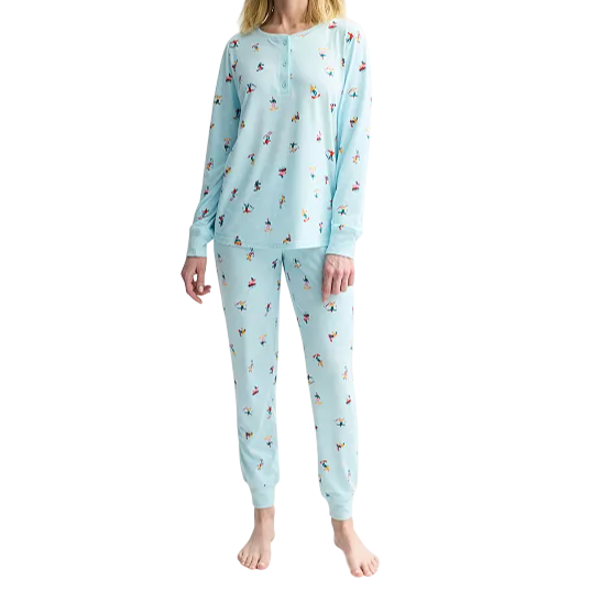 A person is wearing light blue pajamas with a playful pattern of small multicolored figures, consisting of a long-sleeve top and matching pants.