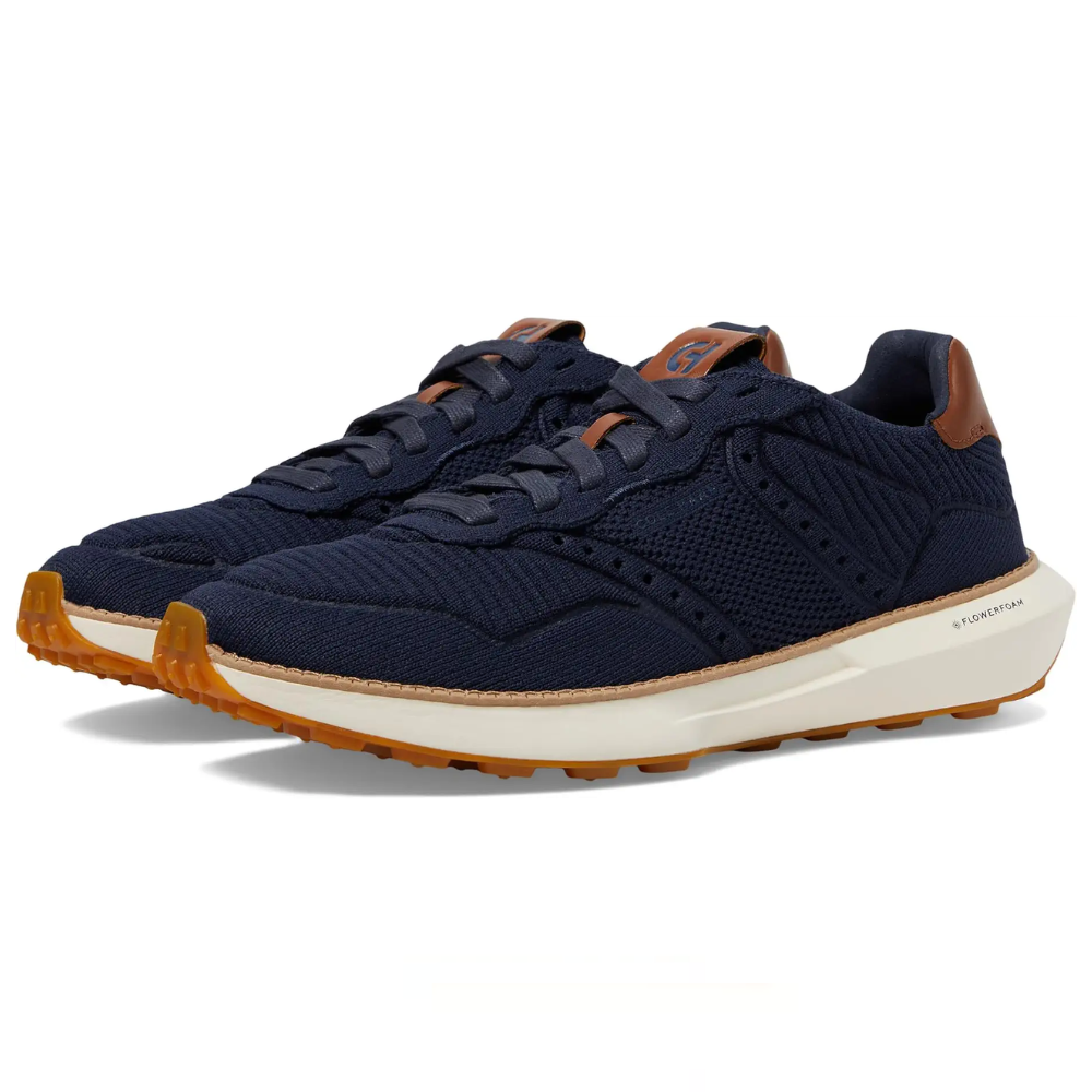 Navy blue sneakers featuring a mesh upper, brown accents, and a white midsole with a gum outsole, designed with \“FlowerFoam\“ technology.