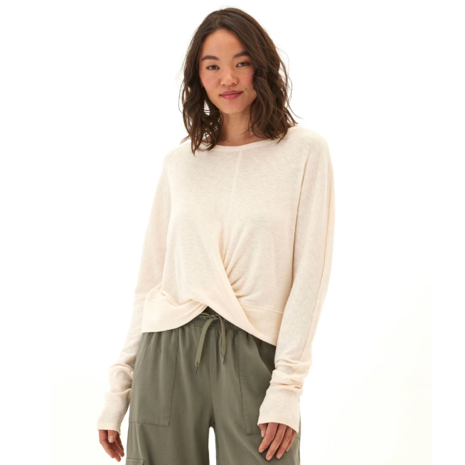 A woman is wearing a light beige long-sleeve top with a twisted front and loose-fitting olive green cargo pants.