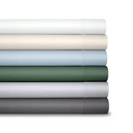 A stack of six rolled-up bed sheets in various colors: white, cream, light blue, dark green, light gray, and dark gray.