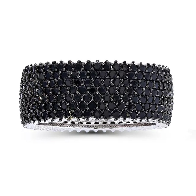 A wide bangle encrusted with multiple rows of small, round black gemstones, set in a silver-tone metal.