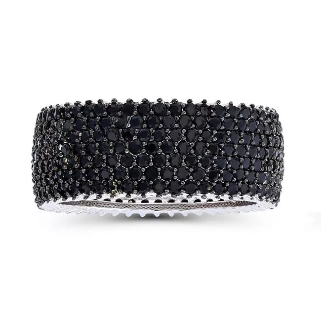 A wide bangle encrusted with multiple rows of small, round black gemstones, set in a silver-tone metal.