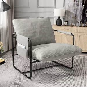A modern gray armchair with black metal frame, featuring a soft cushion and a side pocket for storage. The chair is situated in a stylishly decorated room.