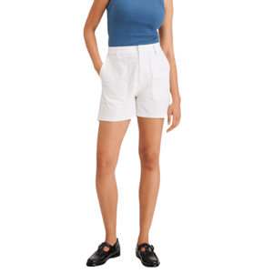 White mid-rise shorts with front pockets, button and zip closure, worn with a blue sleeveless top and black loafers.