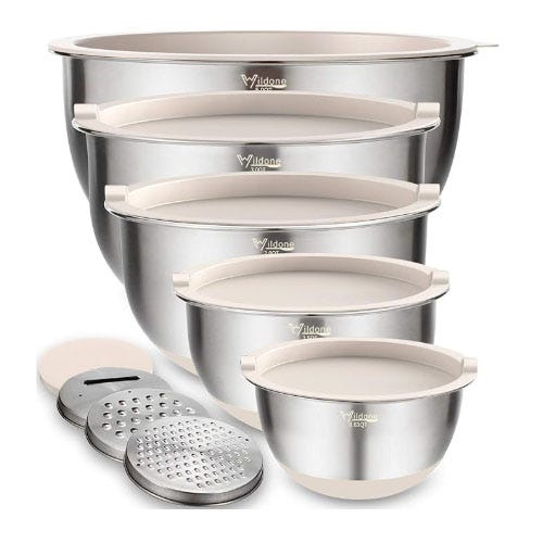 A set of stainless steel mixing bowls with tan lids.