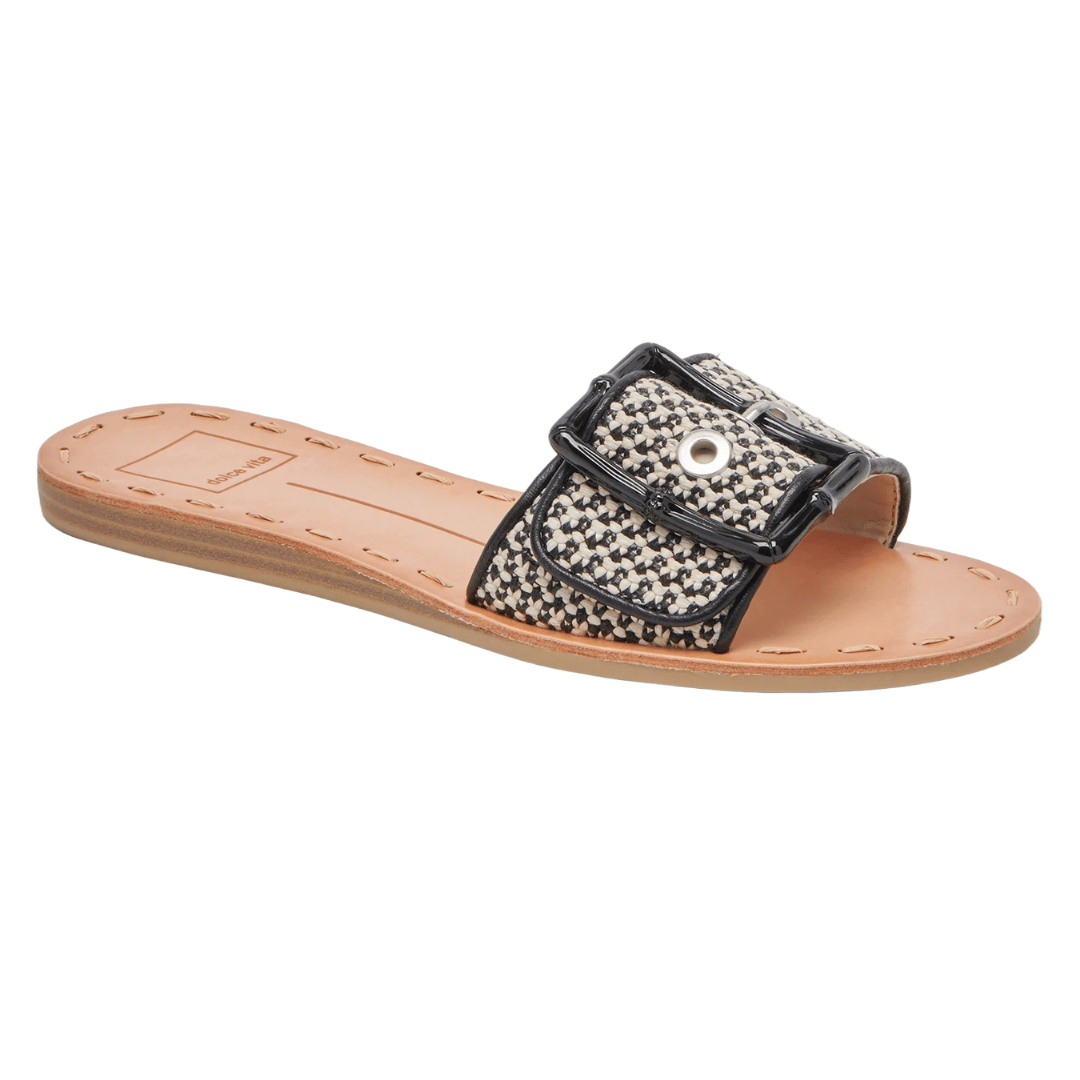 Dolce Vita sandals feature a flat sole, tan brown footbed, and a woven black-and-white strap with a large buckle detail.