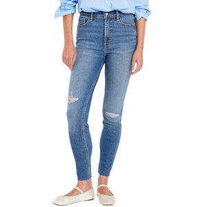 Blue high-waisted skinny jeans with distressed details on the knees, paired with a blue collared shirt and white slip-on flats.