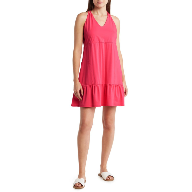 A pink, sleeveless cover-up dress with a V-neck and double strap halter design, featuring a gathered seam at the waist and a ruffled hemline, paired with white slip-on sandals.