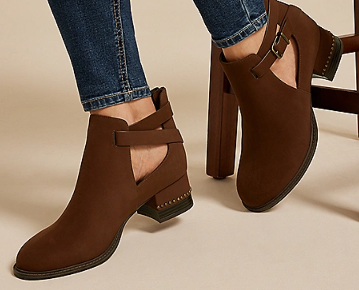 Brown ankle boots with cut-outs, buckle straps, and low block heels, paired with blue jeans.