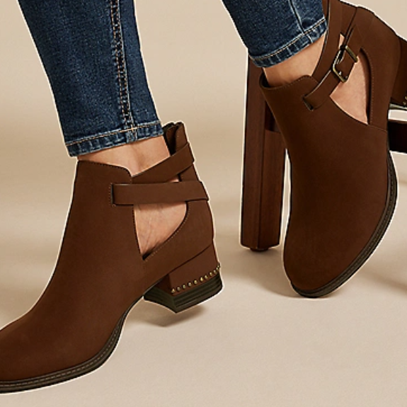 Brown ankle boots with cut-outs, buckle straps, and low block heels, paired with blue jeans.