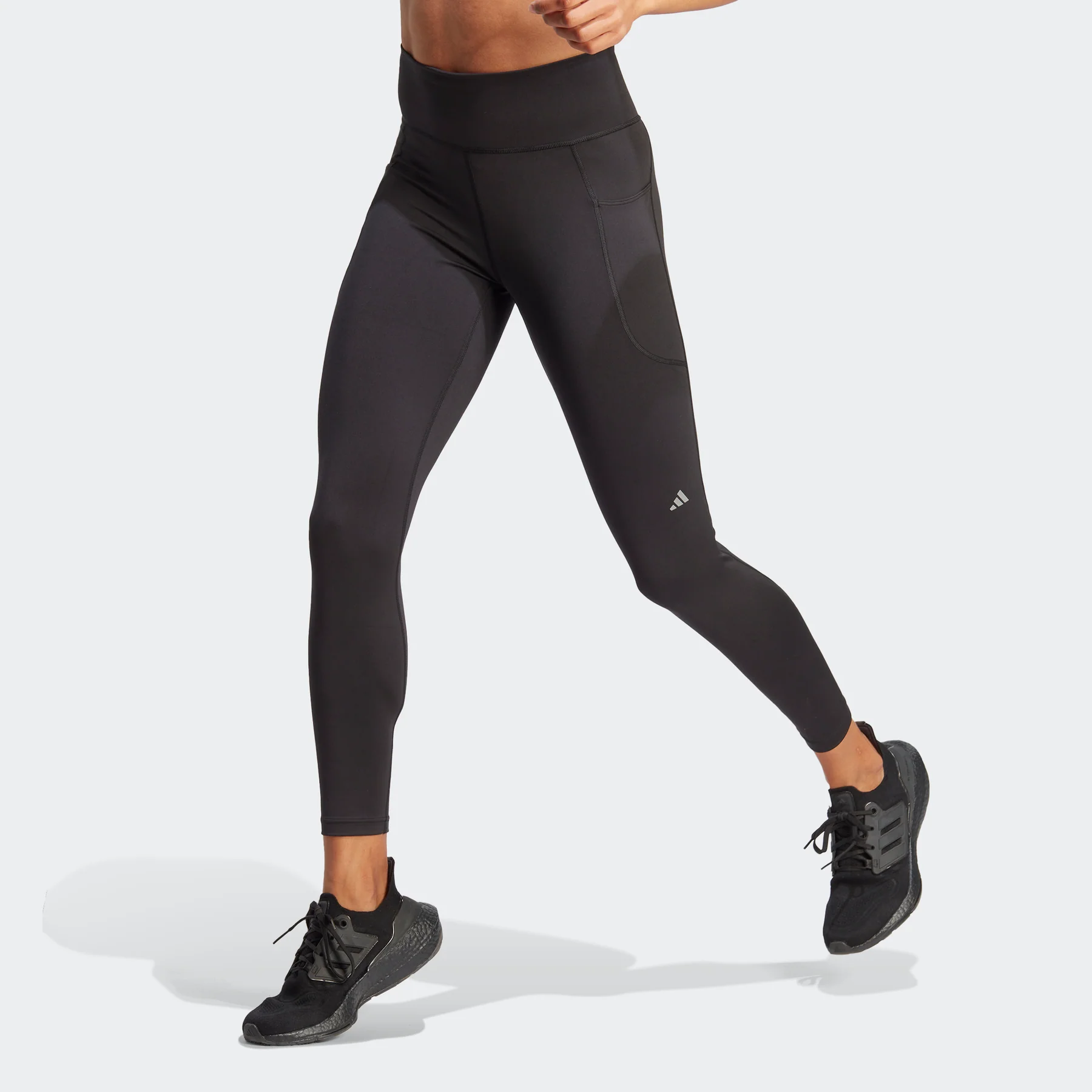 Black athletic leggings paired with black sneakers are displayed, with a visible logo on the left thigh.
