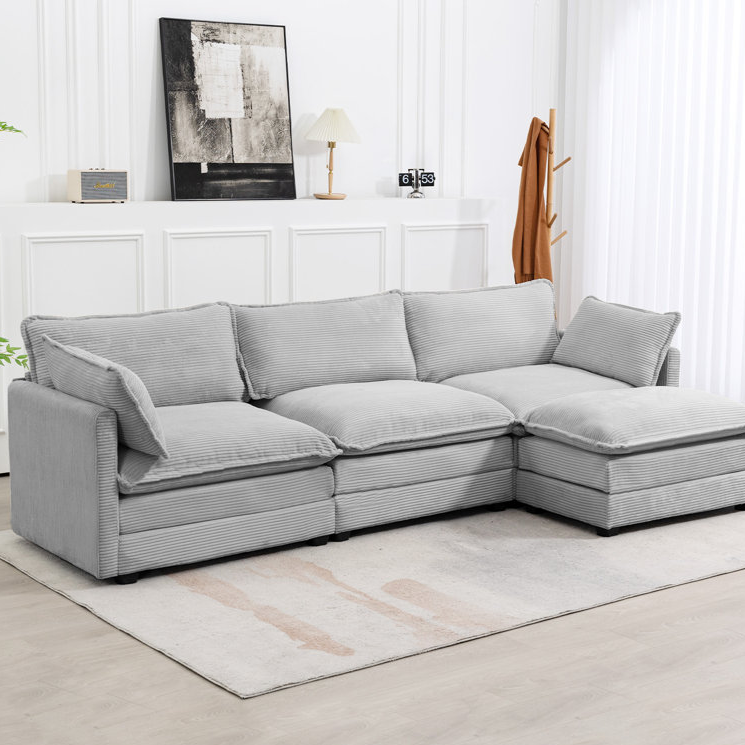 A light gray, 112-inch corduroy sectional sofa with a plush, textured fabric and three spacious seats, featuring a right-side chaise. It rests on a light rug in a modern living room with white walls and minimal decor.
