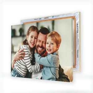 Canvas prints display a joyful family moment with a man hugging two children, showcasing the depth and detail achievable on this type of medium.
