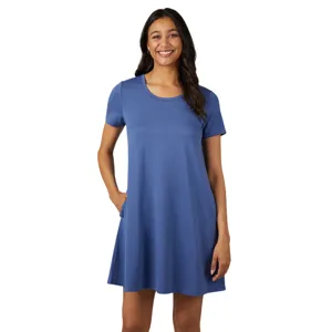 A woman is wearing a blue short-sleeve A-line dress with pockets, standing against a plain gray background.