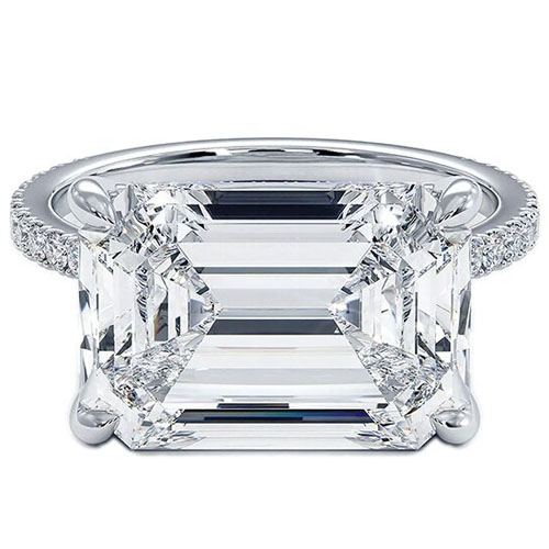 A large emerald-cut diamond ring with a detailed prong setting and a band adorned with small diamonds.