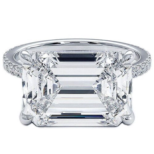 A large emerald-cut diamond ring with a detailed prong setting and a band adorned with small diamonds.