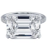 A large emerald-cut diamond ring with a detailed prong setting and a band adorned with small diamonds.