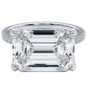 A large emerald-cut diamond ring with a detailed prong setting and a band adorned with small diamonds.