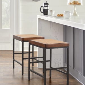 Two backless barstools with brown woven tops and black metal frames are positioned under a white countertop.