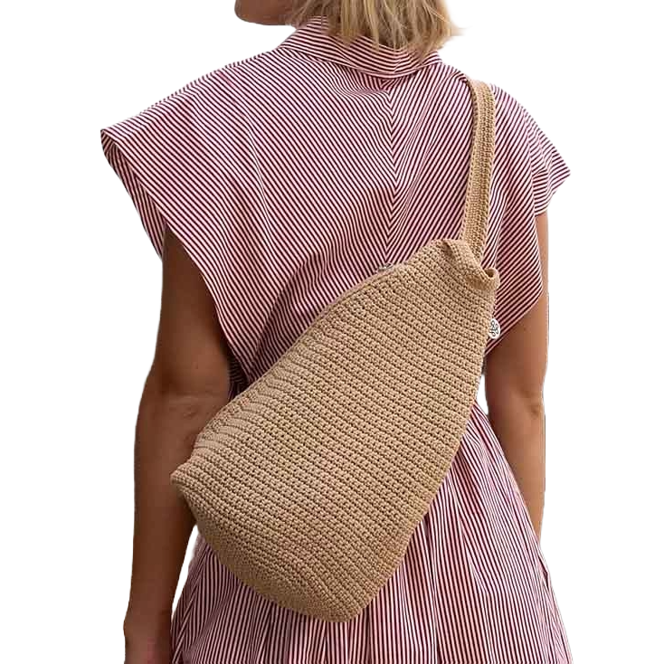 The Sak Geo Sling Crochet Backpack features a textured crochet design in a neutral beige color, worn crossbody. It has a single strap, giving it a casual and stylish appearance.