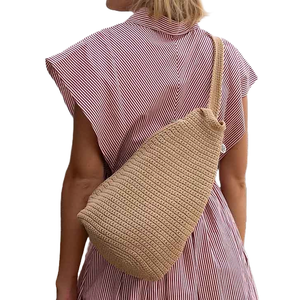 The Sak Geo Sling Crochet Backpack features a textured crochet design in a neutral beige color, worn crossbody. It has a single strap, giving it a casual and stylish appearance.