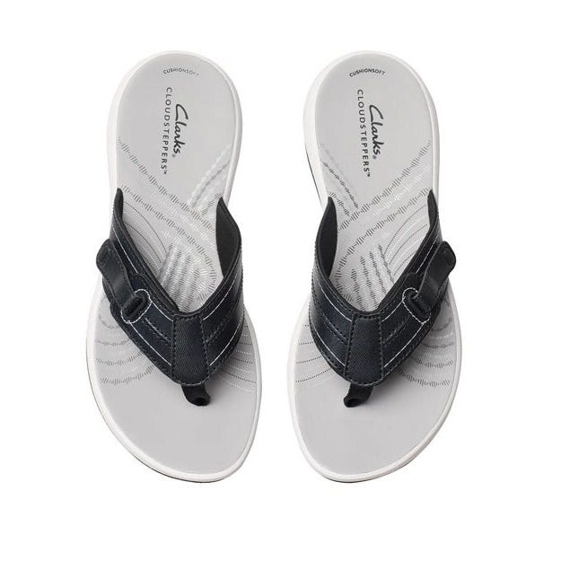 Clarks Sunmaze Loop Sandals feature black textile straps and a cushioned white footbed with textured patterns. They offer Curionsoft Cloudsteppers for comfort.