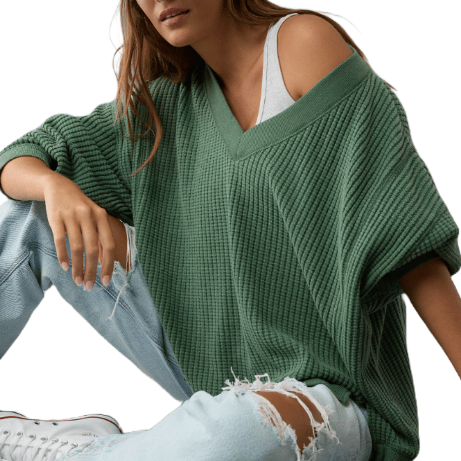 The AE Big Hug Sweater is a loose-knit, oversized green sweater with a V-neckline and slouchy fit, shown layered over a white tank top. It is paired with ripped light wash jeans and white sneakers.