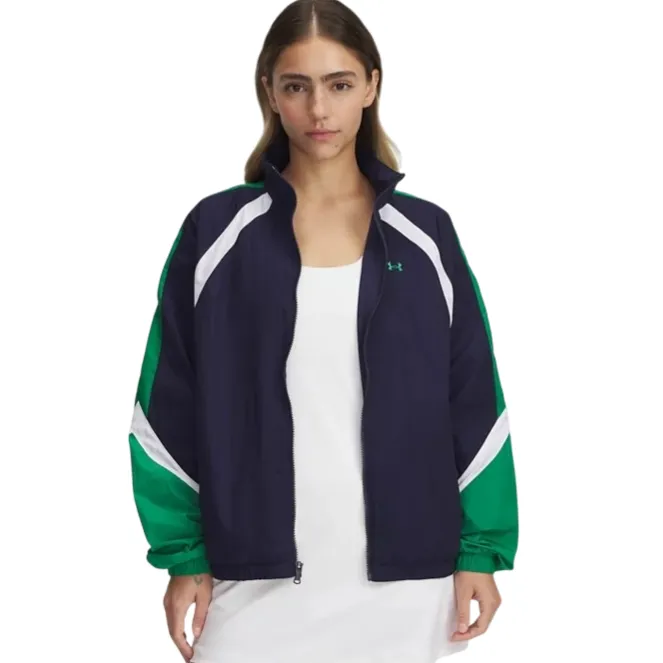 A woman is wearing a navy and green zip-up jacket with white accents from Under Armour, over a white dress.