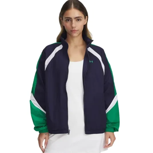 A woman is wearing a navy and green zip-up jacket with white accents from Under Armour, over a white dress.
