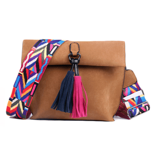 A brown shoulder bag with a colorful, geometric-patterned strap and tassels in blue and pink.