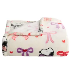 A cozy blanket with a playful design featuring cartoon characters, colorful bows, and hearts, primarily in purple and pink on a white background.