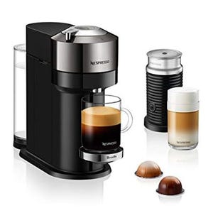 A sleek black Nespresso machine with two espresso cups, accompanied by a frother and two capsules, is shown. The machine features a top-loading capsule mechanism and a simple, modern design.