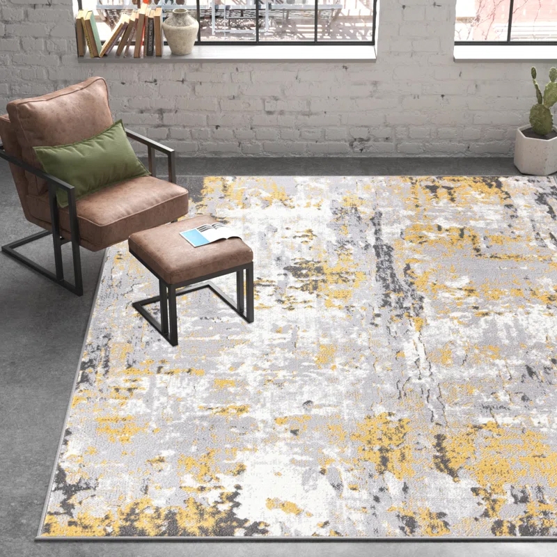 Gray and yellow abstract-patterned rug in a modern room with a brown chair, green cushion, ottoman, and a potted cactus on a concrete floor.