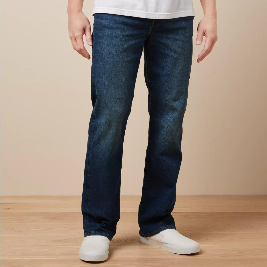 A person wearing dark blue denim jeans and white sneakers.