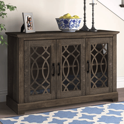 A dark wooden sideboard with three doors featuring decorative lattice glass panels. On top, there is a photo frame, a blue-patterned bowl with fruit, and two candle holders.