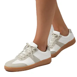 White and light gray sneakers with gum soles, featuring laces and a low-top design.