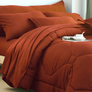 A vibrant red bedding set with pillows, a blanket, and a comforter, featuring a coffee cup and a rolled-up magazine on the bed.