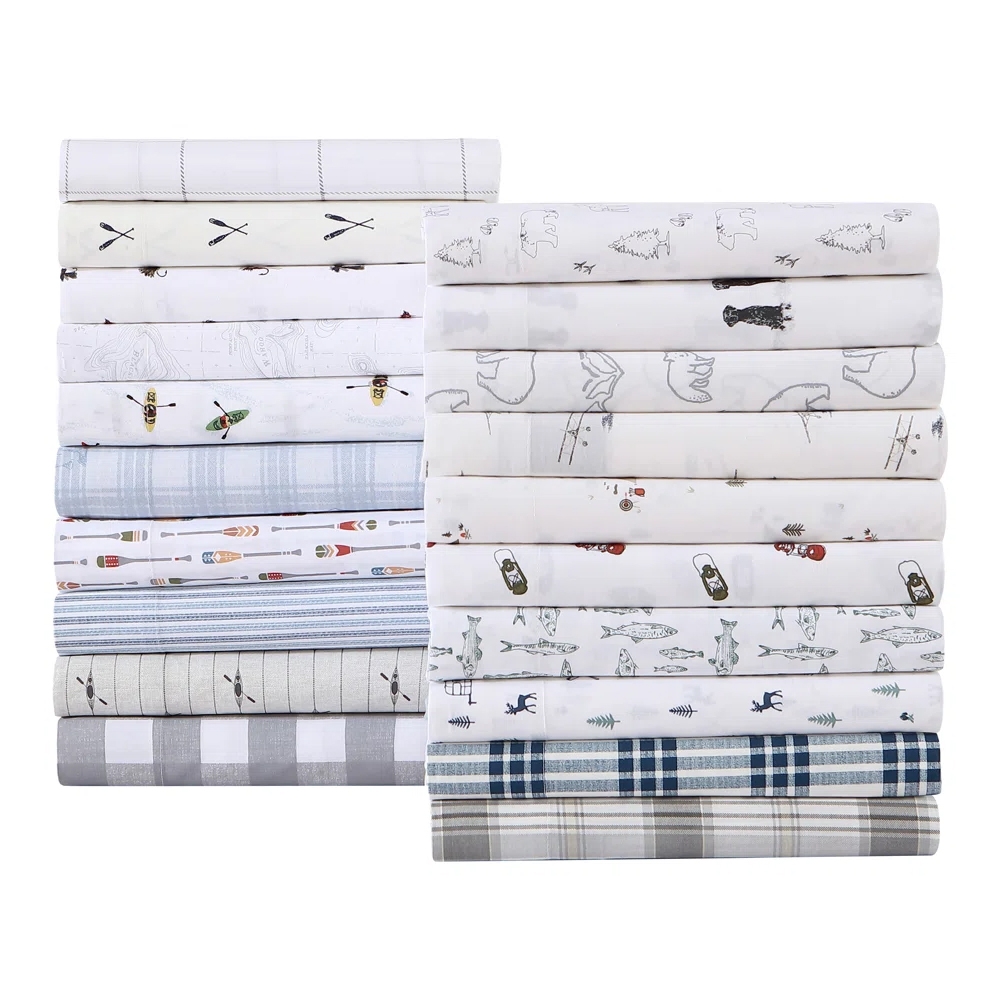 A stack of folded bedsheets featuring various patterns, including checks, stripes, and nature-themed designs like bears and fish. The sheets are primarily in white, blue, and gray tones.