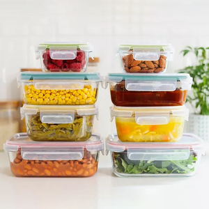Eight glass containers with clear locking lids are stacked, each filled with different foods, including raspberries, almonds, corn, green beans, sauce, pineapple, lettuce, and beans.