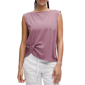 A mauve-colored sleeveless tank top with a twist-front detail, featuring a relaxed fit and a high, subtle boat neckline, paired with white drawstring pants.