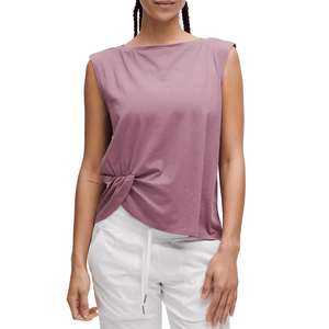 A mauve-colored sleeveless tank top with a twist-front detail, featuring a relaxed fit and a high, subtle boat neckline, paired with white drawstring pants.