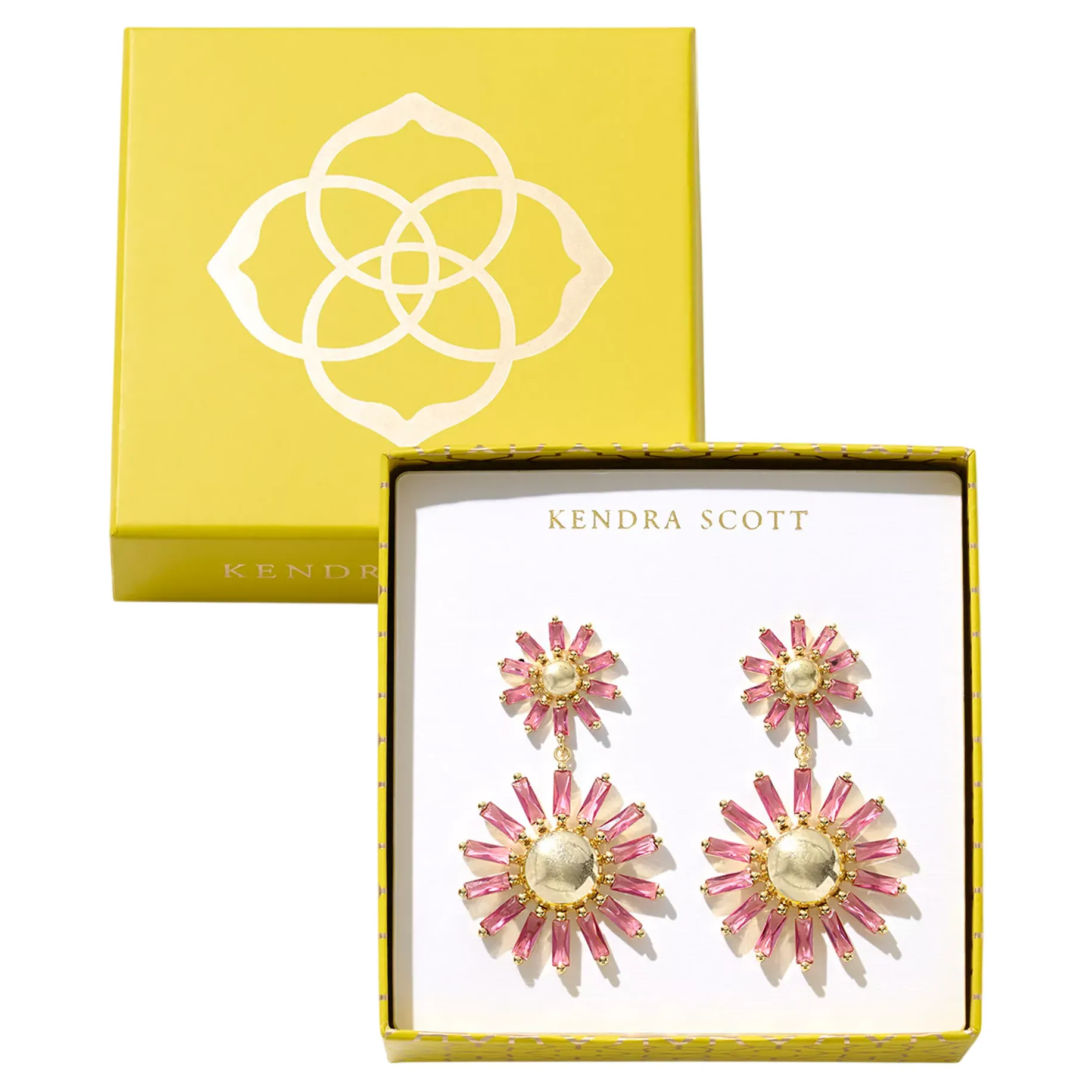 A pair of Kendra Scott earrings, featuring a vibrant design with pink and gold accents, presented in a yellow box with the brand's logo.