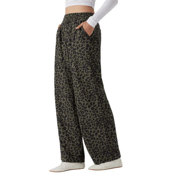 Wide-leg trousers with a black leopard print pattern, elastic waistband, and side pockets, paired with a white long-sleeve top and white shoes.