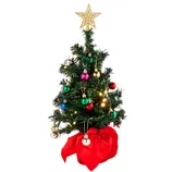 A small decorated Christmas tree with a star topper, colorful ornaments, and lights, set in a red fabric-covered base.