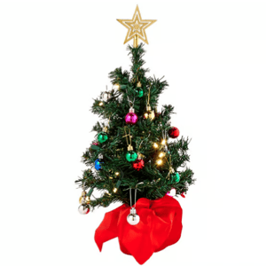 A small decorated Christmas tree with a star topper, colorful ornaments, and lights, set in a red fabric-covered base.