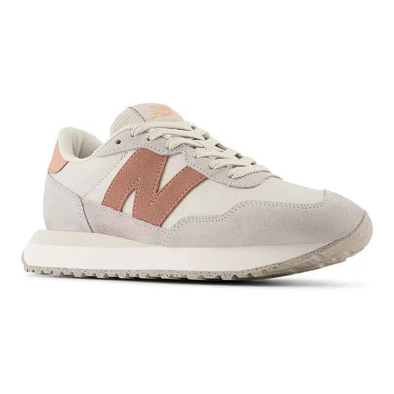 The New Balance Women's 237 Sneakers feature a retro design with a cream base and a pink \“N\“ logo. They have suede and mesh panels, lace-up closure, and a flat, textured rubber sole for casual comfort.