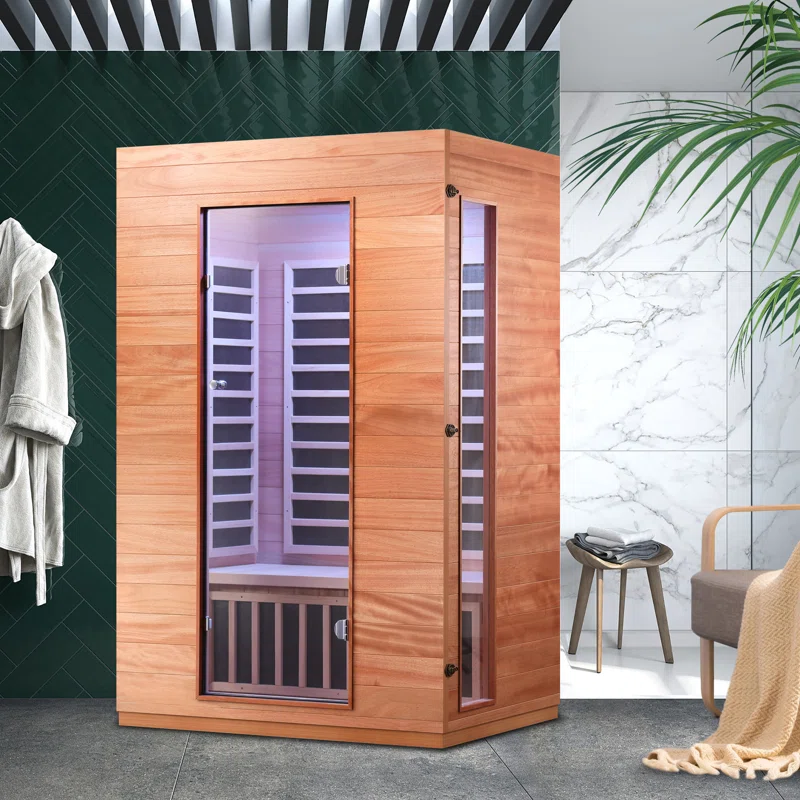 A corner infrared sauna with glass doors and wooden panels, accompanied by bathroom decor including towels and a throw blanket.