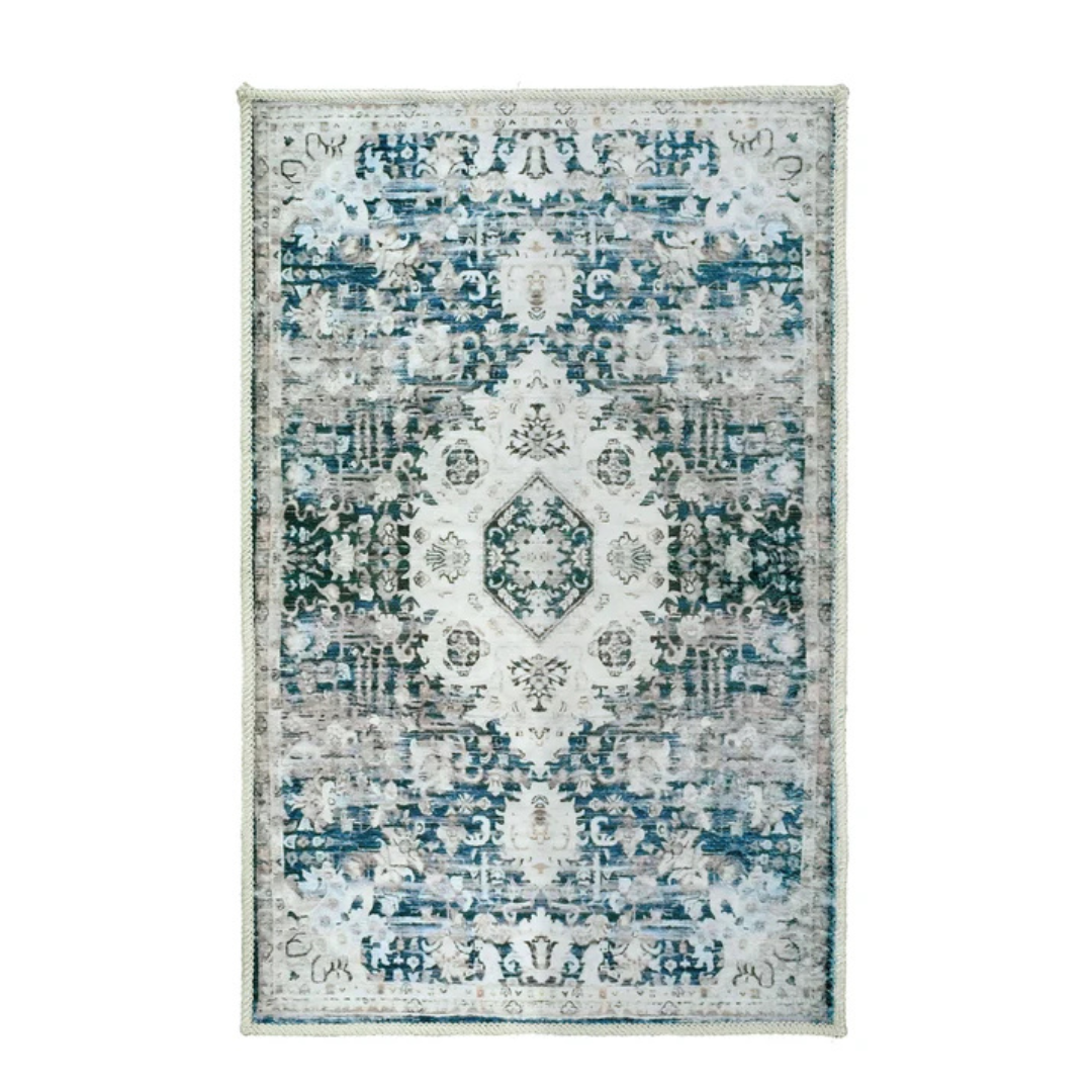 A rectangular area rug with an intricate, symmetrical floral and geometric pattern in shades of blue, grey, and white.
