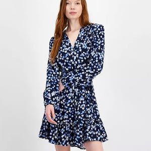 A woman wearing a blue floral dress with long sleeves and a V-neckline.