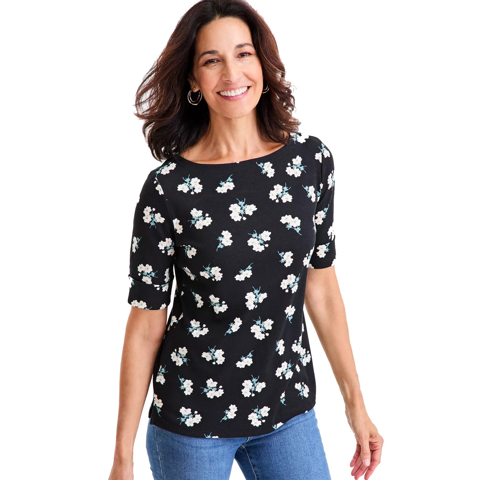 A woman is wearing a black top with small white flower patterns and short sleeves, paired with blue jeans.